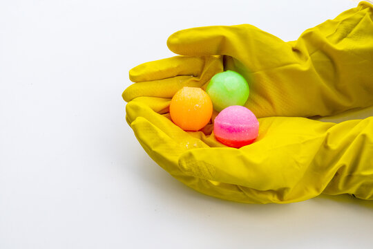 Hands in Yellow Rubber Gloves Holding Colorful Mothballs Isolated on White