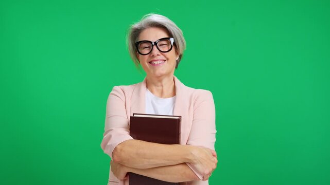 Elegant senior teacher or student holding a book against green background