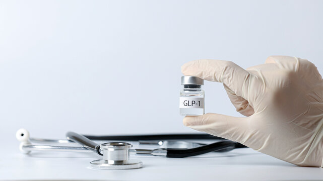 Professional doctor hand holds glp1 vial for hopeful medical weight management treatment next to stethoscope on white background