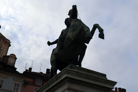 Statua equestre di Polluce in bronzo all'ingresso di Palazzo Reale a Torino, scultura neoclassica dei Dioscuri su piedistallo in marmo con cielo nuvoloso