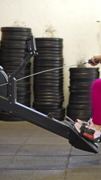 Athletic woman performing rowing machine exercise at the gym