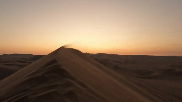 Close up of wind blowing sand on dunes during a vibrant purple sunset in Huacachina, Peru