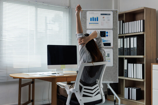 Employee stretching arms at office desk relieving work fatigue