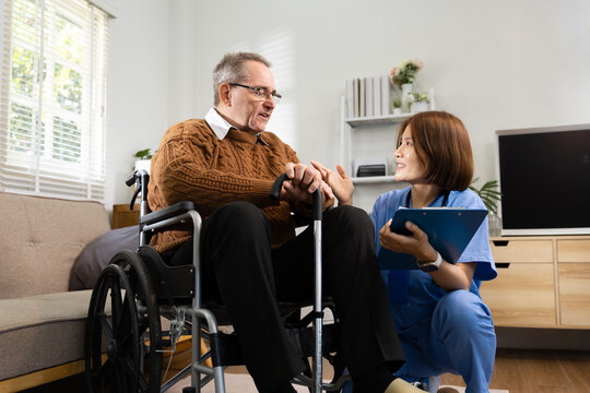 Smiling Caregiver Talking with Elderly Man in Wheelchair