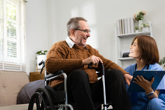 Smiling Caregiver Talking with Elderly Man in Wheelchair