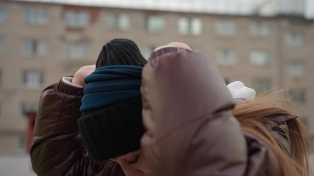 female adjusts beanie in chilly city environment, closeup of woman smoothing her hat amid urban chill, woman carefully straightens her knit cap outdoors with focused intent in cold breeze