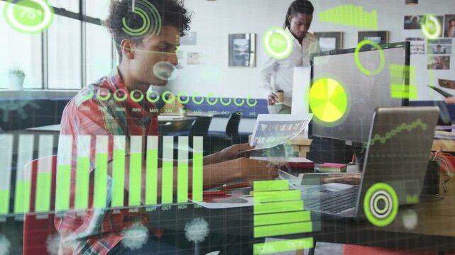 Seated man comparing printed report with laptop in open office, validating data with HUD animating