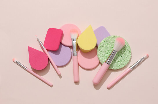 Makeup sponge pads and brushes on a beige background. Beauty products