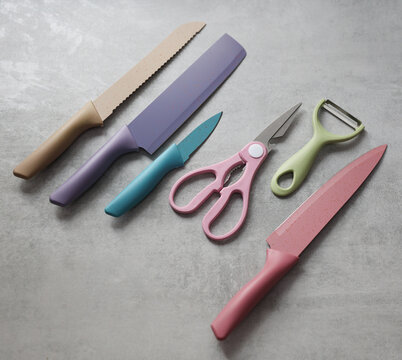 Kitchen scissors and vegetable peeler, set of knives on a concrete countertop