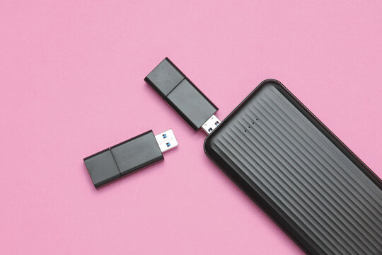 USB flash drives and external hard drive on pink background
