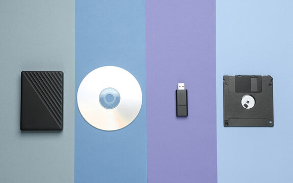 CD disk with floppy disk, USB flash drive and external hard drive on colored background. Digital information media. Flat lay