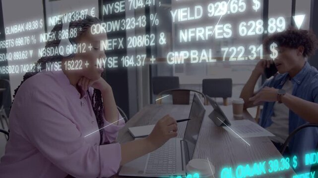 Woman reaching tablet, man ending call at work table for market review, tickers overlaying screens