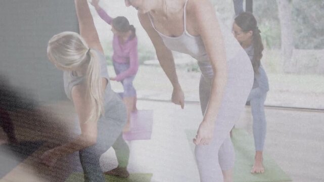 Female coach cueing yoga class moving on mats aligning student into stretch while overlay clearing