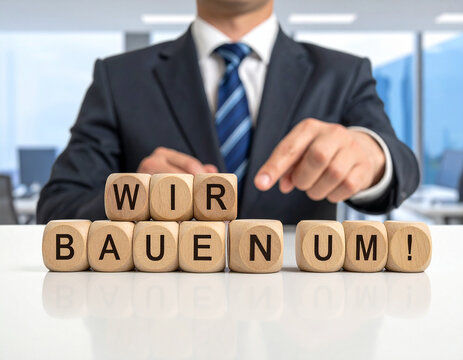 Wir bauen um! - Geschäftsmann zeigt auf den Text "Wir bauen um!"