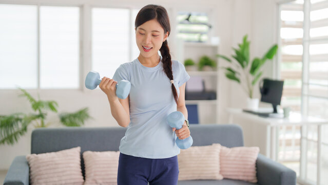 Adult Asian woman home dumbbell workout body conditioning physical activity indoor fitness routine for health and wellness