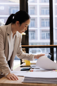 Asian businesswoman organizing documents and reviewing paperwork in office