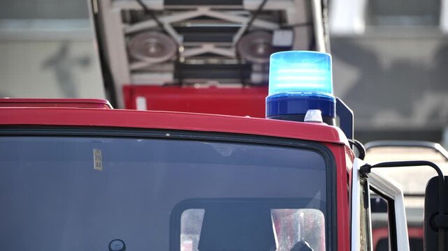 Red fire truck with a blue flashing emergency light indicating a rapid response
