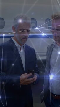 Vertical video: Senior exec tapping phone near plane, partner stepping away, nodes showing biz data