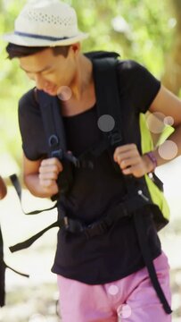 Vertical video: Man on hike buckling strap after pack shift to steady it, woman steadying straps