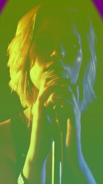 Vertical video: Female singer gripping mic as triangle overlay rising over face and singing music
