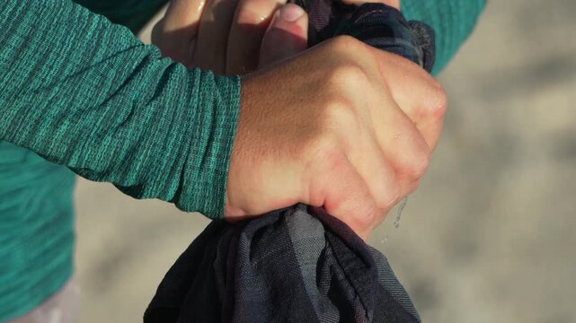 Squeezing water fabric, hands wringing wet cloth outdoors preparing to dry