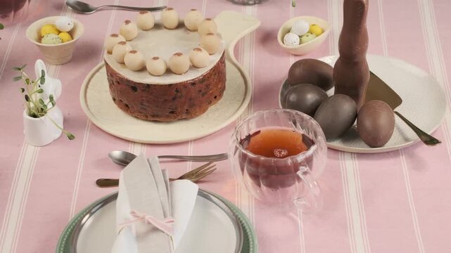 Festive table setting with British Easter Simnel cake, decorated with marzipan balls, on a pink tablecloth. Step-by-step video recipes. Horizontal video. Happy Easter. 
