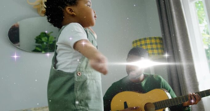 Toddler dancing to guitar music, man strumming and smiling, sparkle effect sweeping over guitar