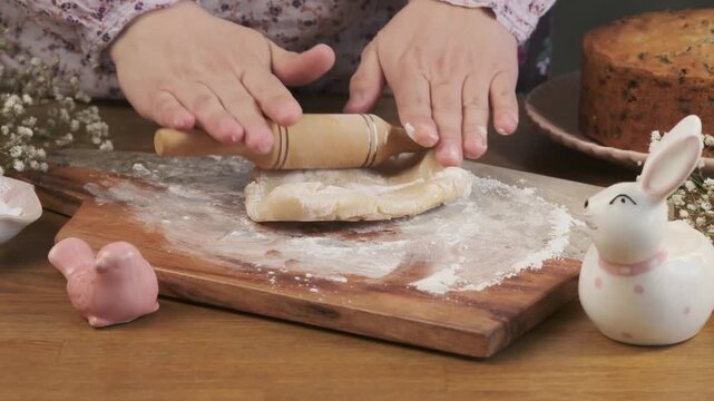 A woman rolls out marzipan with a wooden rolling pin on a board to decorate a cupcake or cake. Step-by-step video recipes. Horizontal video. 