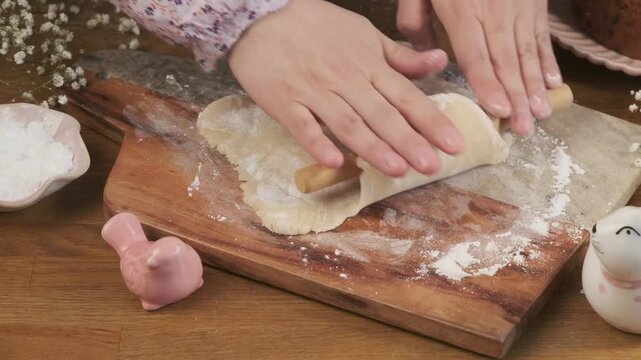 A woman rolls out marzipan with a wooden rolling pin on a board to decorate a cupcake or cake. Step-by-step video recipes. Horizontal video.