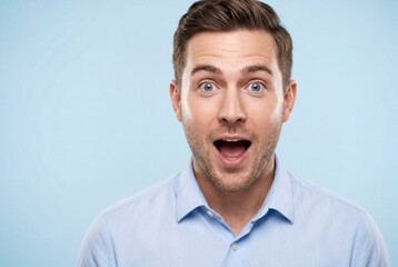 Obraz premium Surprised caucasian man in light blue shirt looking directly at camera on solid blue background
