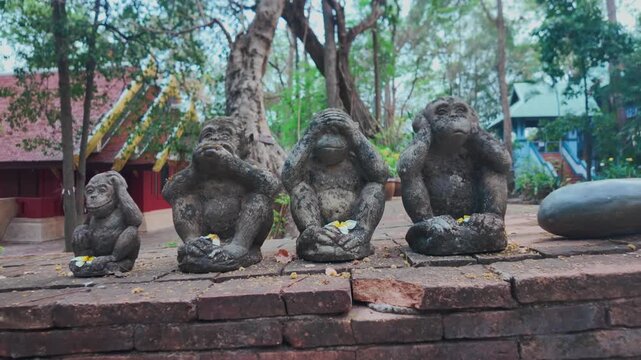 Three wise monkeys stone statues in garden with symbolic meaning, See hear speak no evil sculpture set with traditional Asian philosophy concept 4k