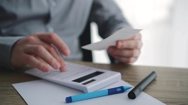 Man checking receipts and calculating budgets with a calculator.
Paper bill payment receipts, online bank payment methods