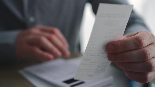 Man checking receipts and calculating budgets with a calculator.
Paper bill payment receipts, online bank payment methods