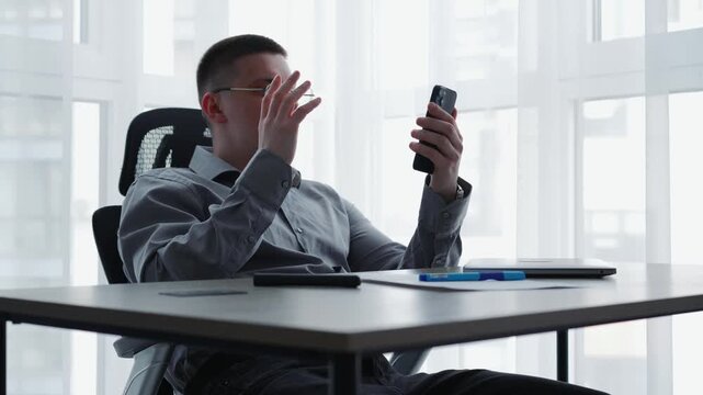 A young businessman having a video call on his smartphone in the office.
Online conference, resolving work issues, online meeting via video link