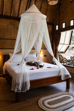 Resort bedroom showing prepared bed with white mosquito net and decorative flowers