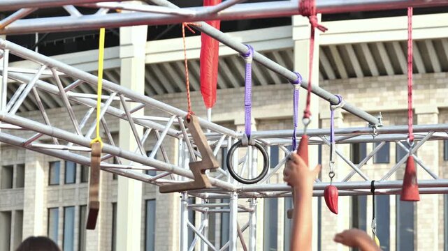 Athlete tackling ninja warrior obstacle course with various hanging grips outdoors