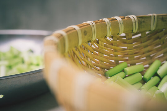 Artisanal close up of fresh green garlic scapes in woven bamboo basket with bokeh