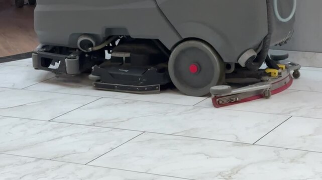 Industrial floor cleaning machine scrubbing tiles, cleaning and maintenance concept, janitorial service, hygiene, commercial equipment, indoor cleaning process