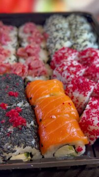 Philadelphia rolls, close-up sushi. Vertical video. Salmon sushi, assorted rice rolls. Ginger and chopsticks.