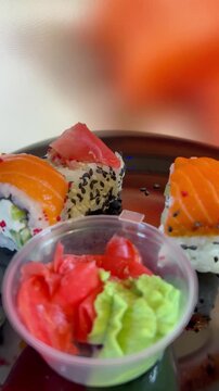 Philadelphia rolls, close-up sushi. Vertical video. Salmon sushi, assorted rice rolls. Ginger and chopsticks.