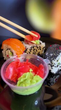 Philadelphia rolls, close-up sushi. Vertical video. Salmon sushi, assorted rice rolls. Ginger and chopsticks.