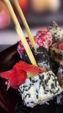 Philadelphia rolls, close-up sushi. Vertical video. Salmon sushi, assorted rice rolls. Ginger and chopsticks.