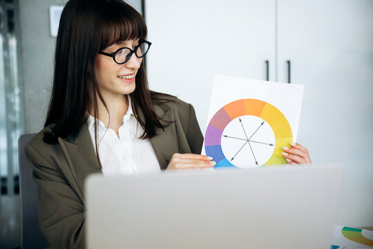 Professional woman discussing design concepts, showing a color wheel chart during an online video conference