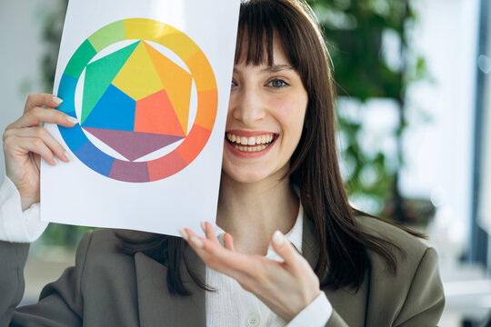 Woman presenting a color wheel chart, demonstrating color theory and palette selection in a creative business environment