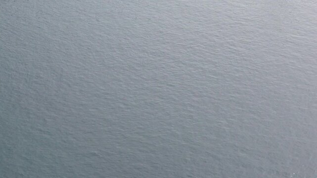 Elevated view of silvery sea surface with fine ripples, subtle movement texture background