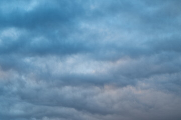 Obraz premium Gloomy sky scene. Dark layered clouds create ambiance. Overcast bluegray clouds form textured landscape. Dense stratocumulus clouds with subtle lighting and moody atmosphere