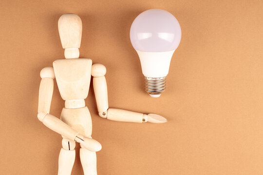 Wooden mannequin with outstretched arm under light bulb, idea and inspiration concept