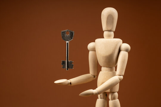 Wooden figure grasping for key on beige background, answer and breakthrough symbolism
