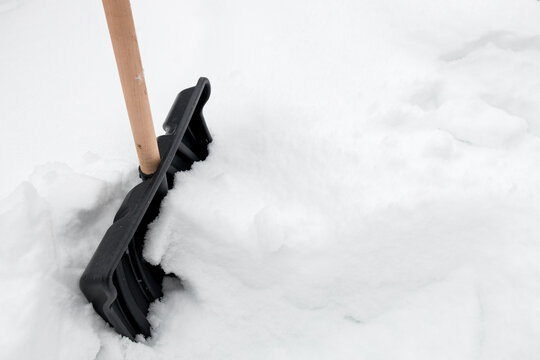 Wooden-handled snow shovel planted in winter snowdrift