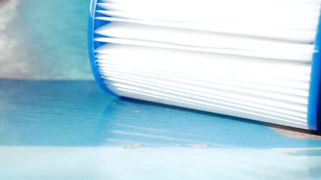 Reusable pool cartridge filter in blue backdrop. Cleaning and maintenance, water filter replacement. Cleanliness, order, system, control, modernity. Soft depth of field. Minimal.
